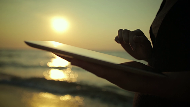 Женщина использует планшетный ПК на берегу моря
 - Кадры, видео