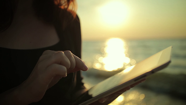 Женщина использует планшетный ПК на берегу моря
 - Кадры, видео