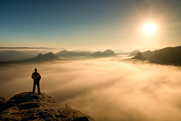 Muž stojí na vrcholu pískovcové skály v Sasku Švýcarsko park a sledovat Sun. krásný zázrak přírody - Fotografie, Obrázek