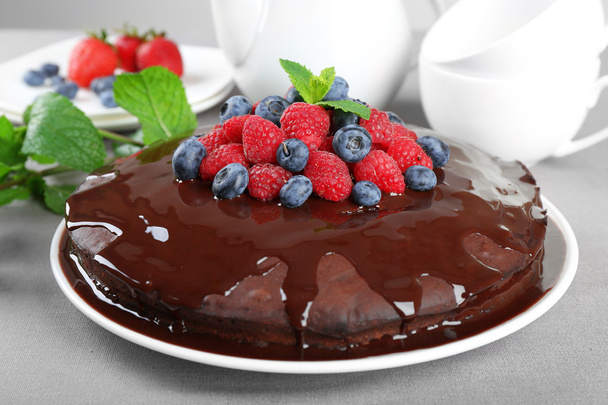 Delicious chocolate cake with summer berries on grey tablecloth, closeup - Fotó, kép