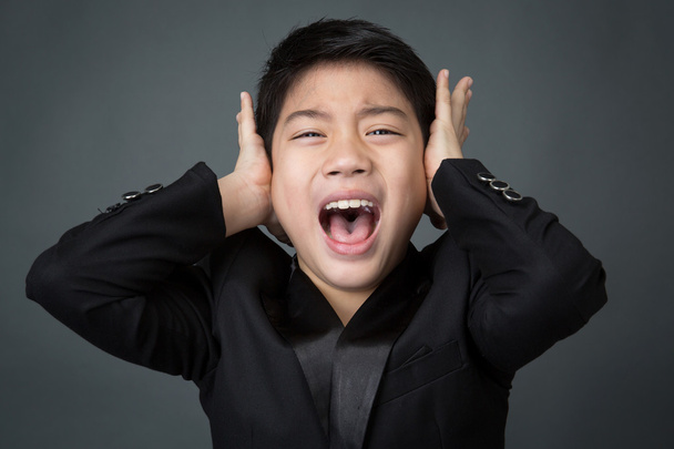 kleiner asiatischer Junge im schwarzen Anzug aufgebracht, Depressionsgesicht - Foto, Bild