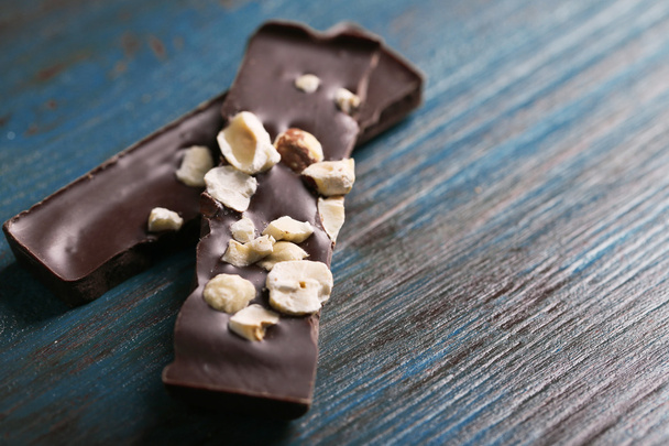 Black chocolate pieces with nuts on color wooden background - Photo, Image