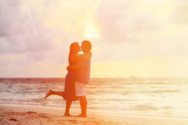 Jonge romantisch paar op het strand bij zonsondergang - Foto, afbeelding
