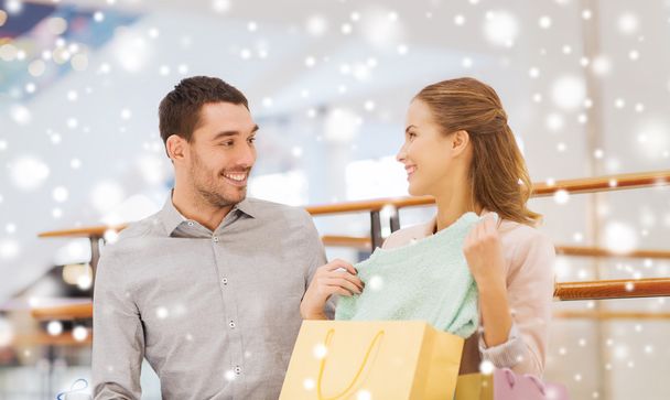 glückliches junges Paar mit Einkaufstüten in Einkaufszentrum - Foto, Bild