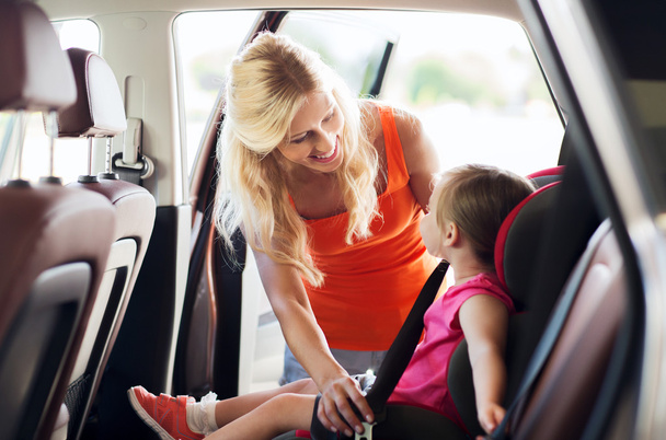 happy mother fastening child with car seat belt - Foto, Bild
