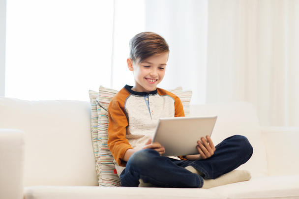 smiling boy with tablet computer at home - 写真・画像