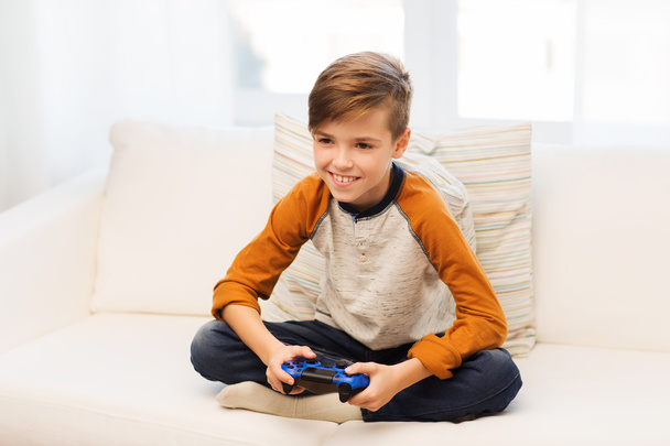 happy boy with joystick playing video game at home - Foto, afbeelding