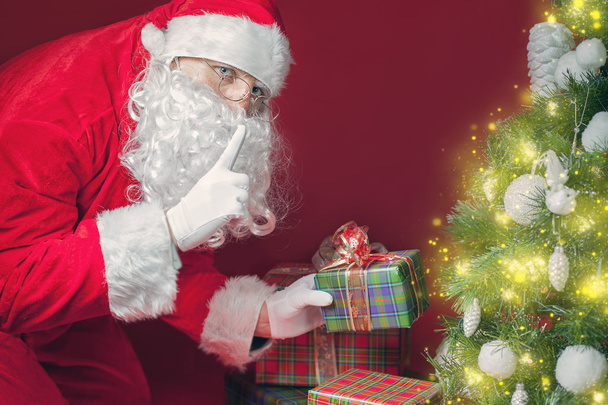 Santa Claus putting gift box or present under Christmas tree - Φωτογραφία, εικόνα