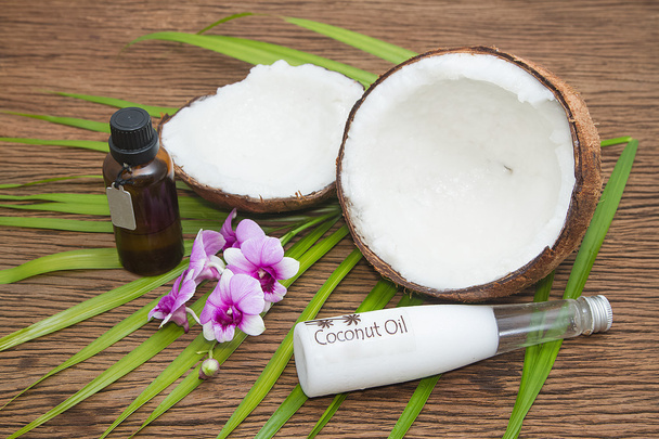 Coconut oil in bottles with fresh coconuts on wooden background - Foto, Imagem