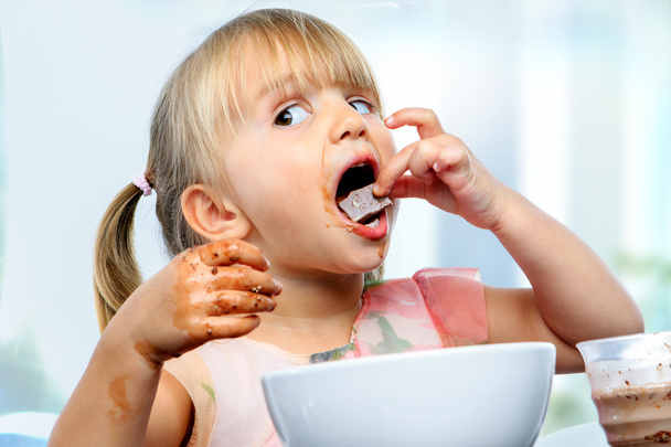 Little girl eating chocolate breakfast. - Foto, afbeelding
