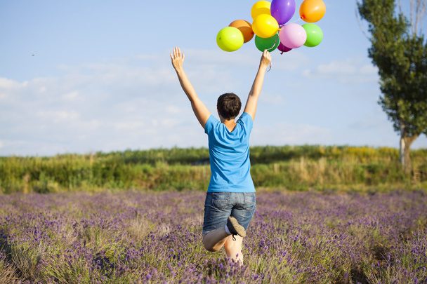 Jovem com balões coloridos no campo de campismo
 - Foto, Imagem