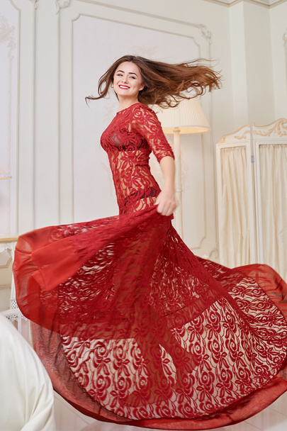 Femme heureuse dans une robe rouge sautant du lit
 - Photo, image