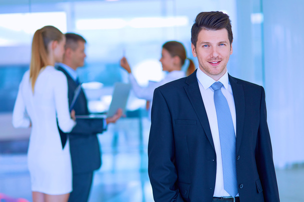 Portrait of young businessman in office with colleagues in the background - Photo, image