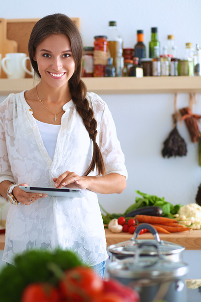 Young woman using a tablet computer to cook in her kitchen - Photo, image