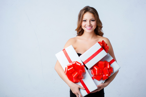 Donna felice con scatole bianche con archi rossi in mano
. - Foto, immagini