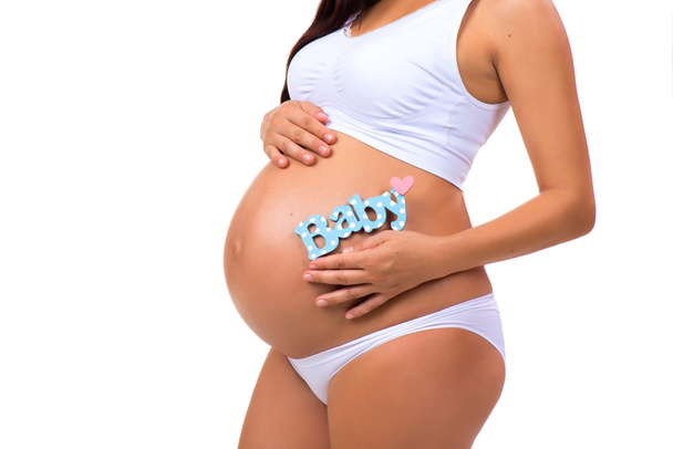 Blízká březí břicho s modrou etiketou "Baby" pro novorozence. - Fotografie, Obrázek