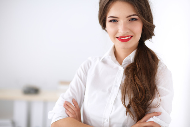 Attractive businesswoman standing near wall in office - Photo, Image