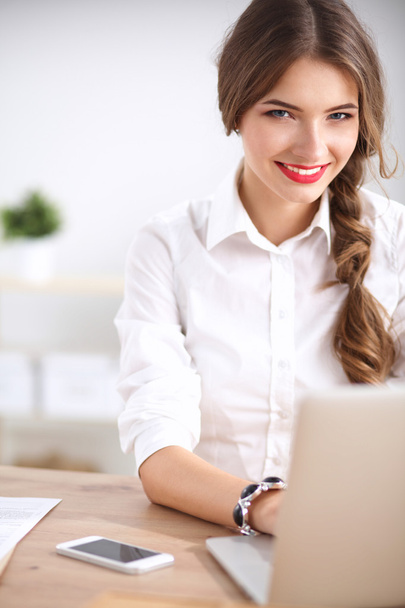 Attractive businesswoman sitting  on desk in the office - Foto, afbeelding
