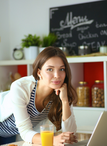 atrakcyjna młoda kobieta za pomocą laptopa i siedzi w kuchni - Zdjęcie, obraz