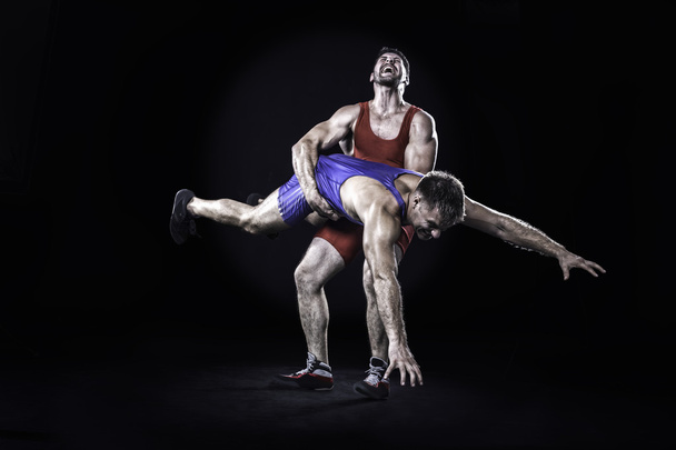 Freestyle wrestler throwing action isolated on black background - Photo, Image