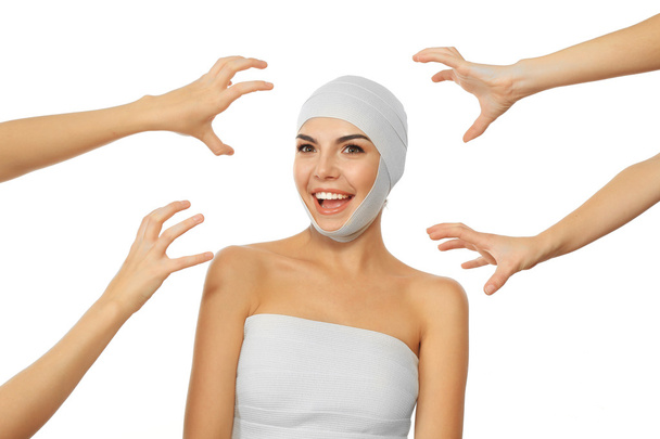 Jovem mulher emocional com uma bandagem elástica na cabeça e mãos ao redor dela, isolado em branco
 - Foto, Imagem
