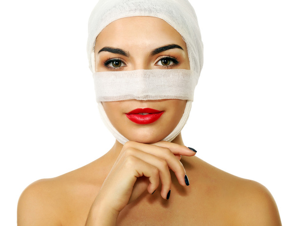 Young beautiful woman with a gauze bandage on her head and nose, isolated on white - 写真・画像