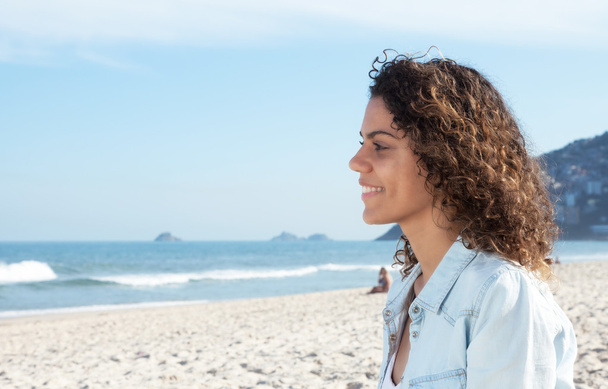 Сміється Латинська жінка на пляжі і дивиться в океан
 - Фото, зображення