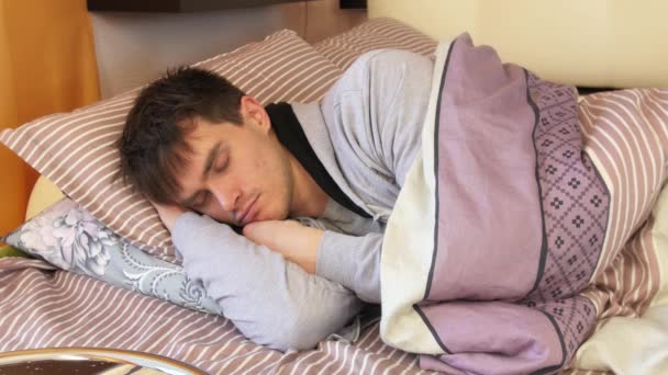 Fiatal férfi az ágyban alszik. Hányódás és fordítás - Felvétel, videó