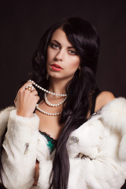 Beautiful girl with dark hair in a white fur coat - Photo, image