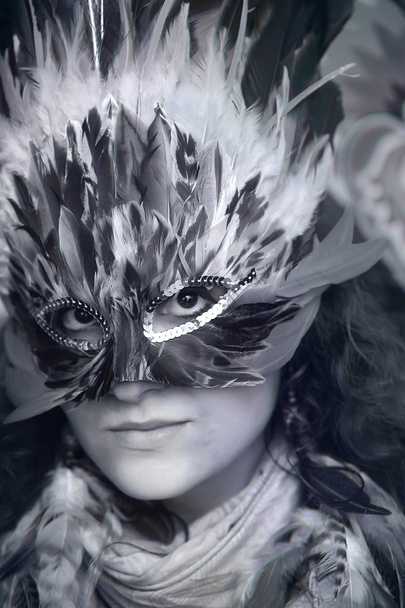 眼との接触、明るいカラフルな背景にカラフルな羽毛カーニバル マスクをした若い女性のメイクアップ アーティスト. - 写真・画像