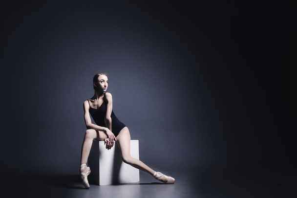 Young ballerina in dark cloth is dancing in a dark of the photostudio - Foto, imagen