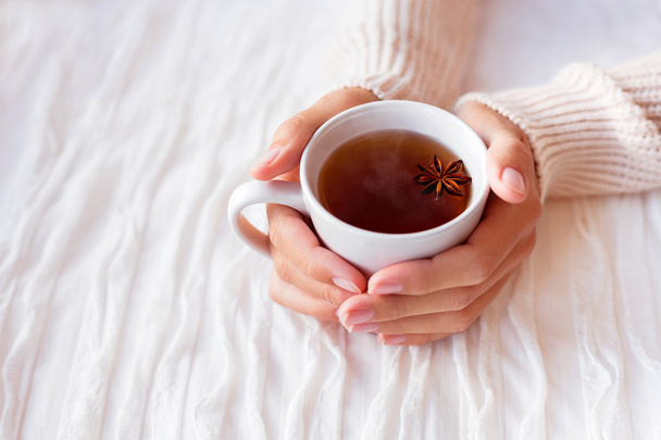 Las mujeres tienen una taza de té caliente con estrella de anís. Acogedora mañana en casa
. - Foto, Imagen