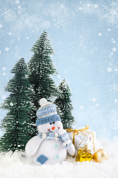 Різдвяний сніговик з подарунками на сніжному тлі
 - Фото, зображення