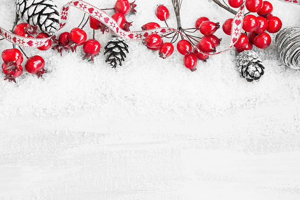 Marco de la cinta de la decoración de Navidad con las bayas rojas y el cono del pino
 - Foto, imagen