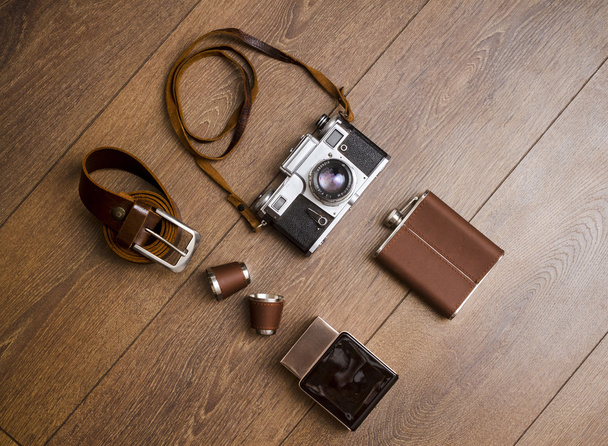 Caméra vintage et ceinture en cuir sur sol en bois
 - Photo, image