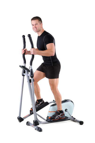 jonge man doen oefeningen op elliptische trainer - Foto, afbeelding