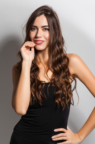 Brunette with magnificent hair with a snow-white smile in a blac - Photo, Image
