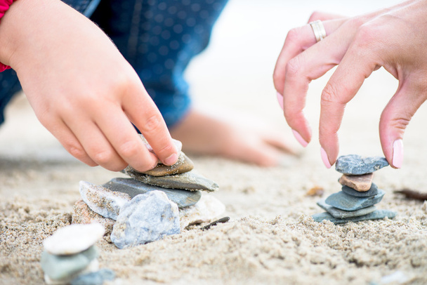 Hands placing Stones on the Stone Pyramids on sand - Photo, Image