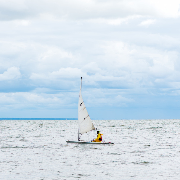 Osamělý plachetnice v moři, zamračená obloha a stříbrné vodě - Fotografie, Obrázek