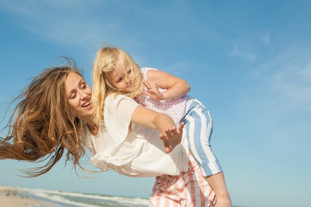 Mother and daughter having fun playing on the beach - Foto, Imagem