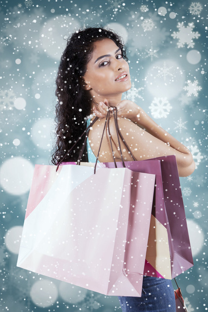 Woman holds shopping bags with snowflake background - Foto, Bild