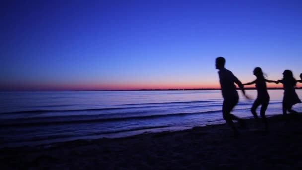 Young people running on the sea shore early in the morning. - Záběry, video