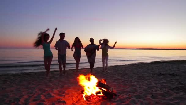 Young people meet dawn near campfire. - Materiał filmowy, wideo