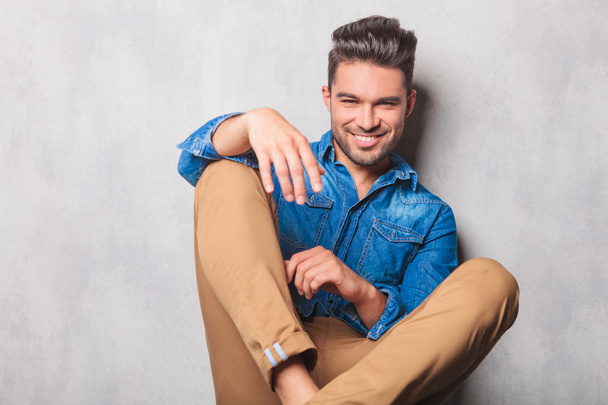smiling man sitting in studio background legs crossed posing - Photo, Image