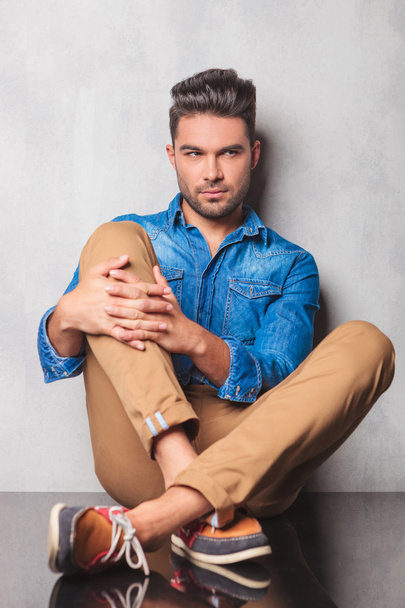 stylish man sitting in studio background legs crossed holding hi - Φωτογραφία, εικόνα