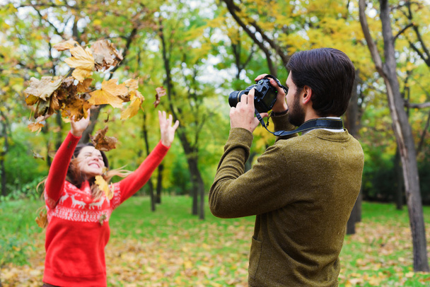 young happy couple taking photos in autumn park - Zdjęcie, obraz