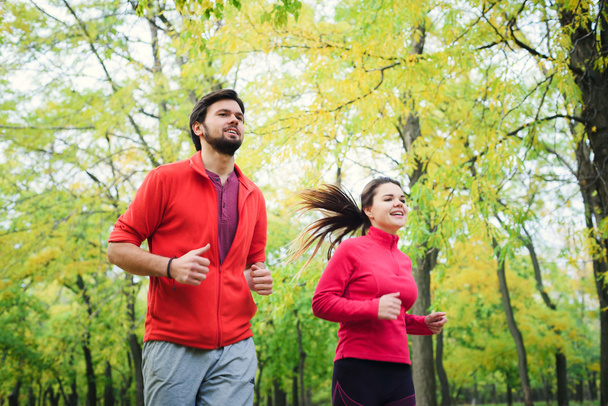 young caucasian couple running in autumn park, couple jogging together - Foto, imagen