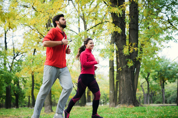 young caucasian couple running in autumn park, couple jogging together - Фото, зображення