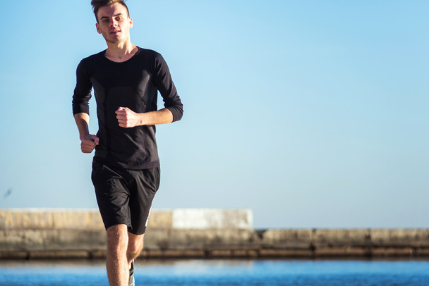 Running man. Male runner jogging during the sunrise on beach - 写真・画像