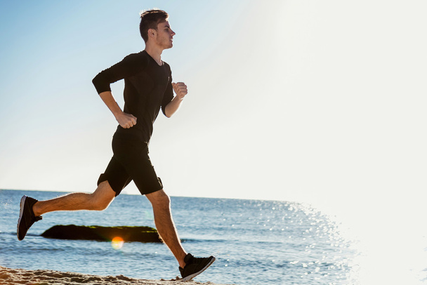 Juokseva mies. Mies juoksija lenkkeily auringonnousun aikana rannalla
 - Valokuva, kuva